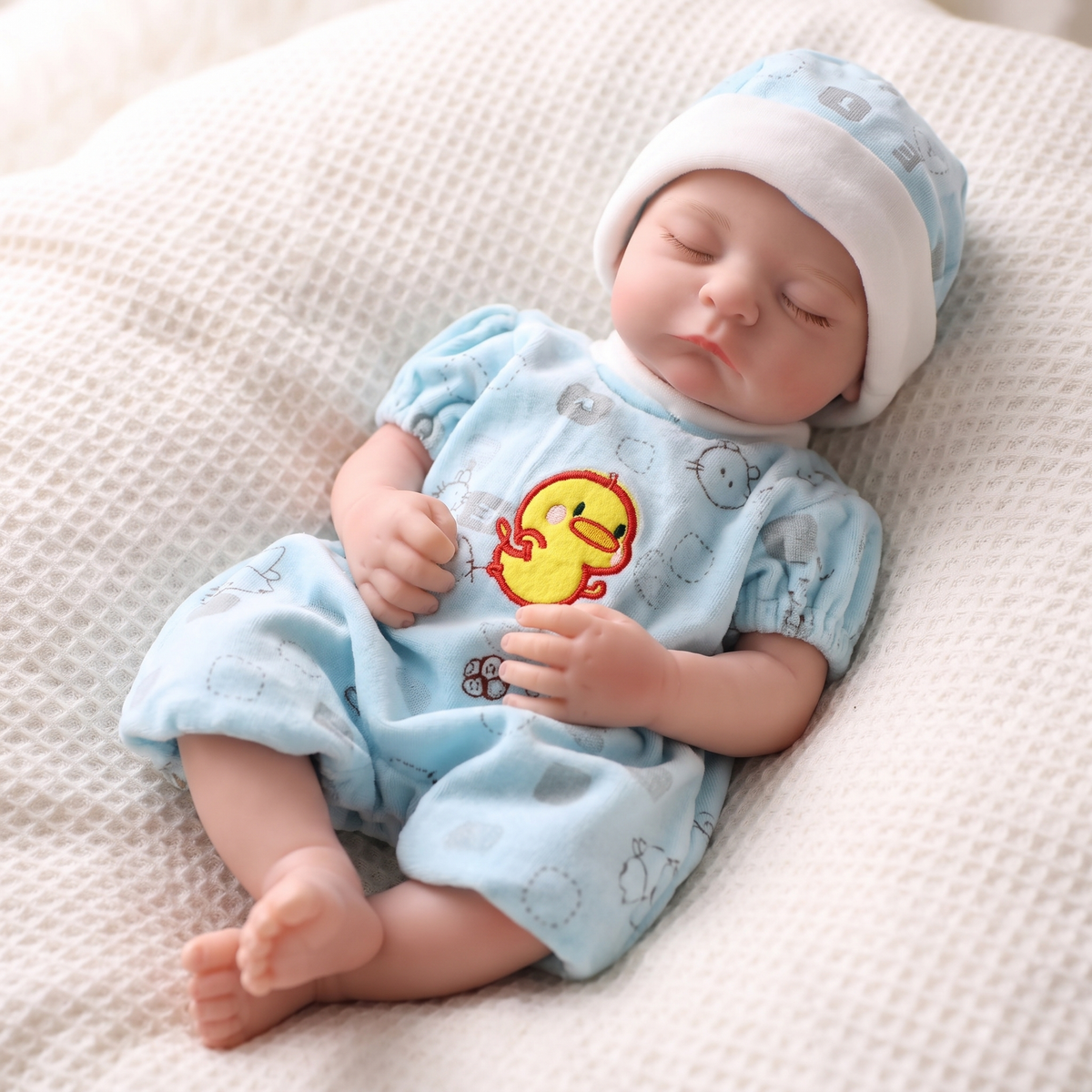 Noah doll in baby blue duck romper and striped hat